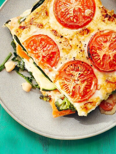 Detailfoto: Lasagne belegt mit Tomaten auf Teller. Lasagne belegt mit Tomaten auf Teller.