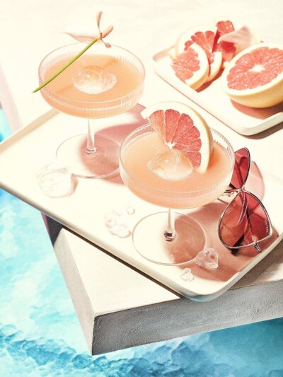 Food Fotograf fotografiert Grapefruit Drinks mit Sonnenbrille am Pool. Grapefruit Drinks mit Sonnenbrille am Pool.