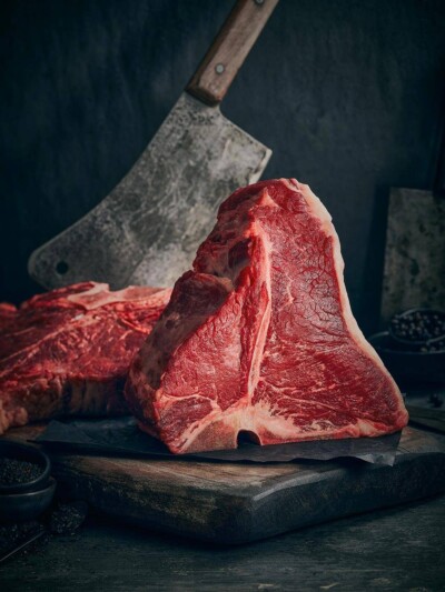 T-Bone Steaks fotografiert auf dunklem Untergrund mit Messer