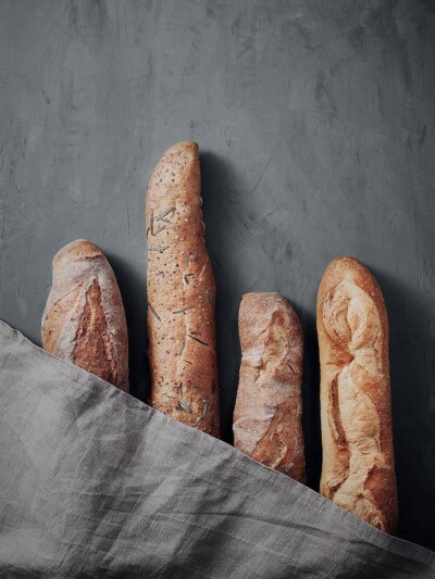 Werbung Bäckerei Essen, Baguettes unter Tuch auf blauem Untergrund. Baguettes unter Tuch auf blauem Untergrund.